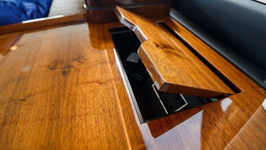 Wooden desk surface with a small open compartment revealing electrical outlets and a sleek design backdrop.